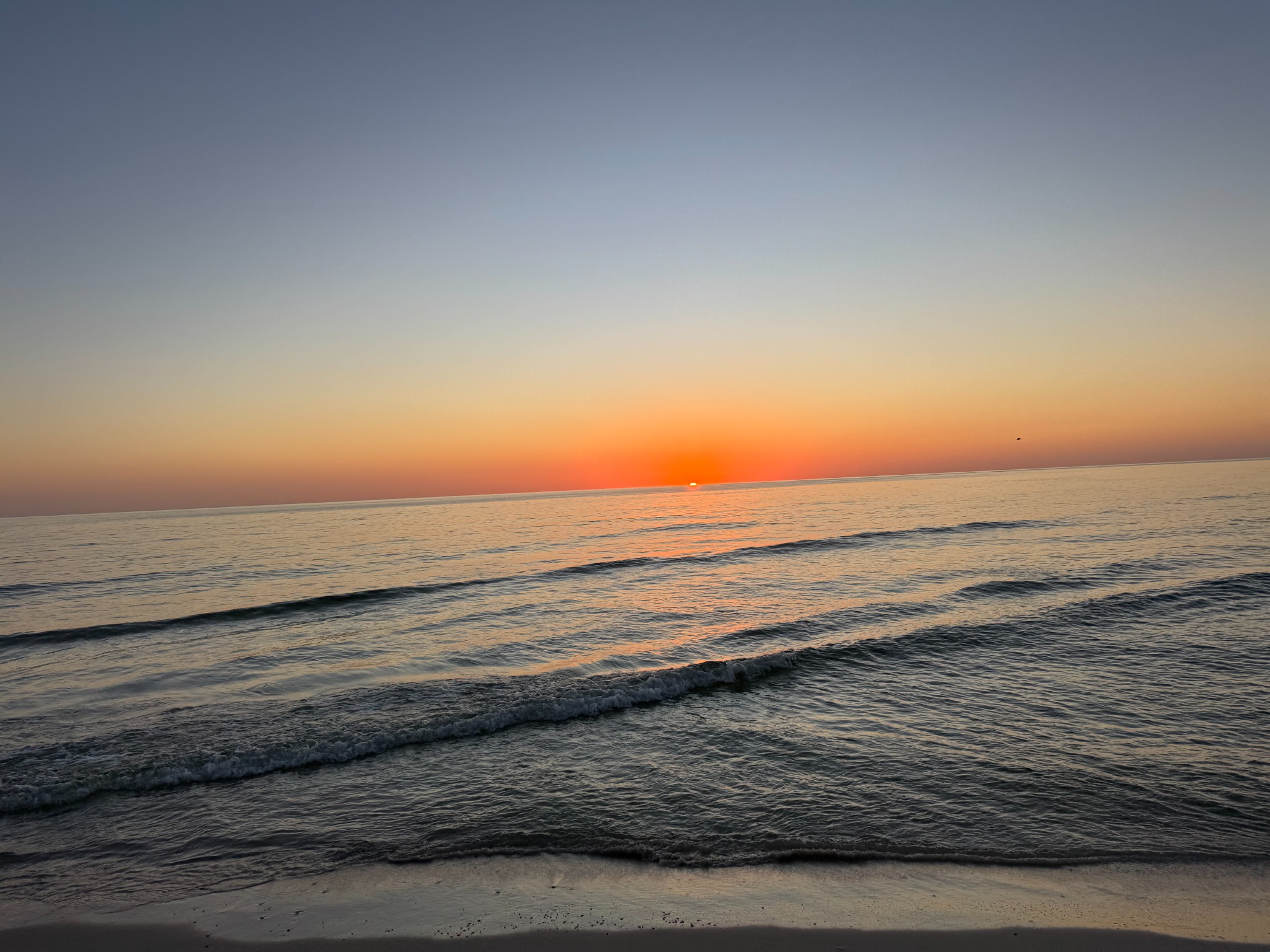 Orange sun setting over gentle water at Cape San Blas